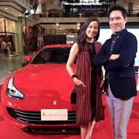 a man and woman standing next to a red ferrari sports car