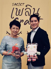 a man and a woman holding stuffed animals in front of a sign