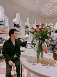 a man sitting at a bar with a vase of roses