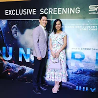 a man and woman standing in front of a movie poster