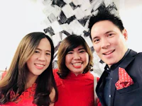 three people posing for a photo in a red dress