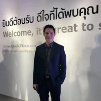 a man in a suit standing in front of a welcome sign