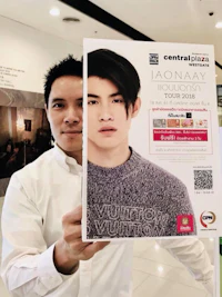 a man holding up a poster in a mall