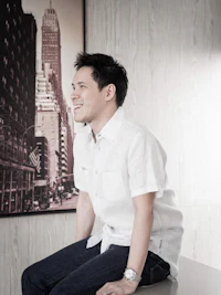 a man in a white shirt sitting on a table in front of a picture